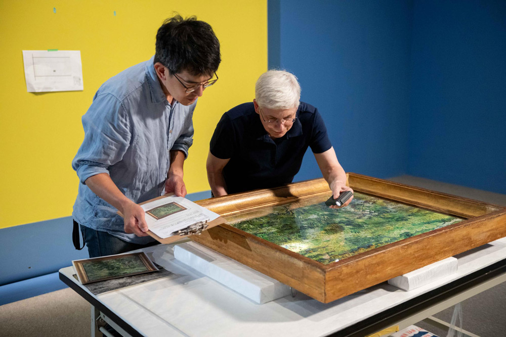 奇美博物館《英國國家藝廊珍藏展》布展過程，兩館的修復師仔細檢視梵谷的作品〈長草地與蝴蝶〉。圖-奇美博物館提供