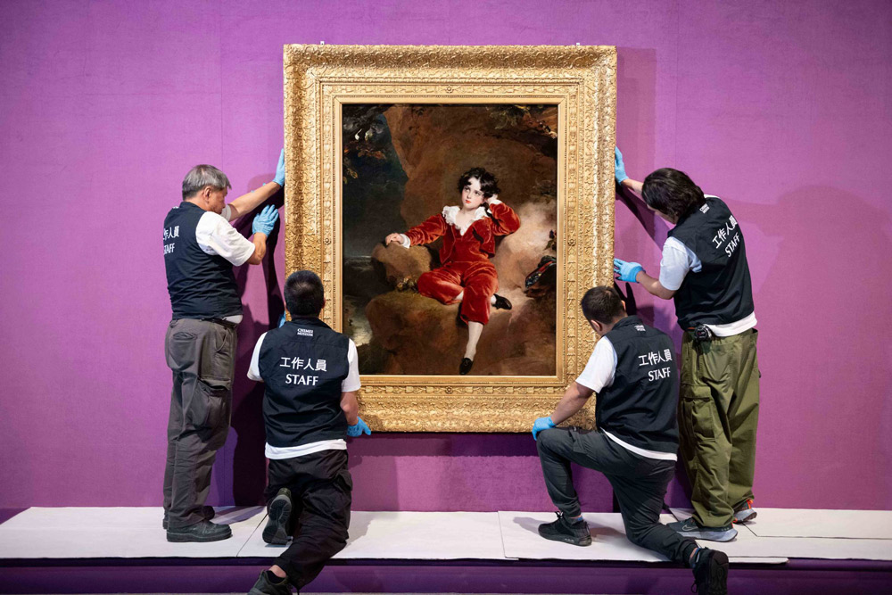 奇美博物館《英國國家藝廊珍藏展》布展過程，工作人員將勞倫斯的作品〈查爾斯．威廉．蘭姆頓肖像〉（紅衣男孩）掛於牆上。圖-奇美博物館提供